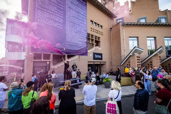 A pink flare outside Contact with a crowd of people. There is a large banner on the side of the building.