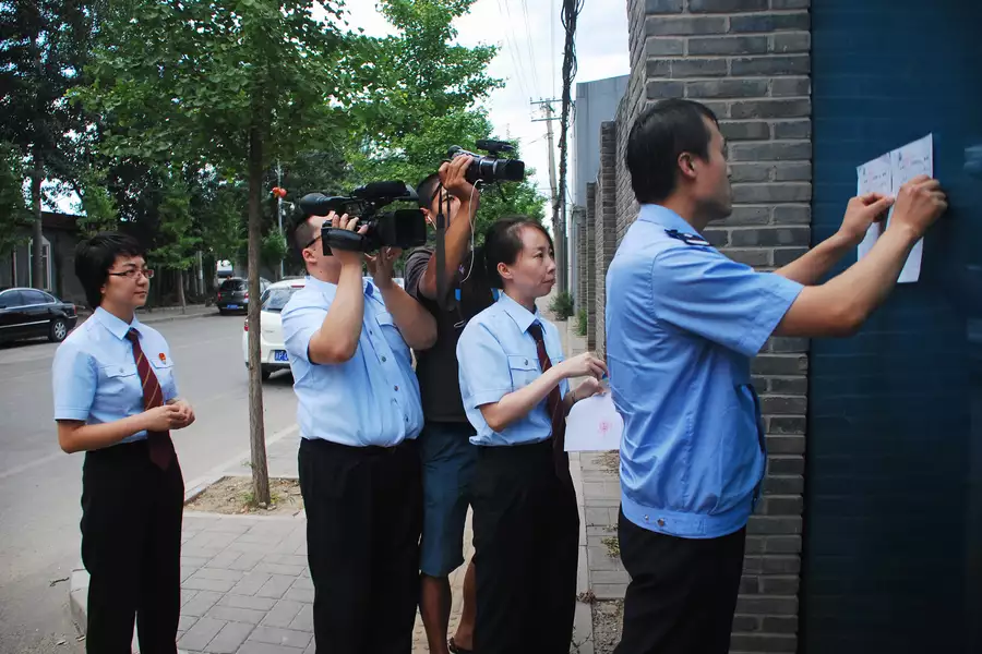 Still of people wearing uniforms filming a notice being placed on a building