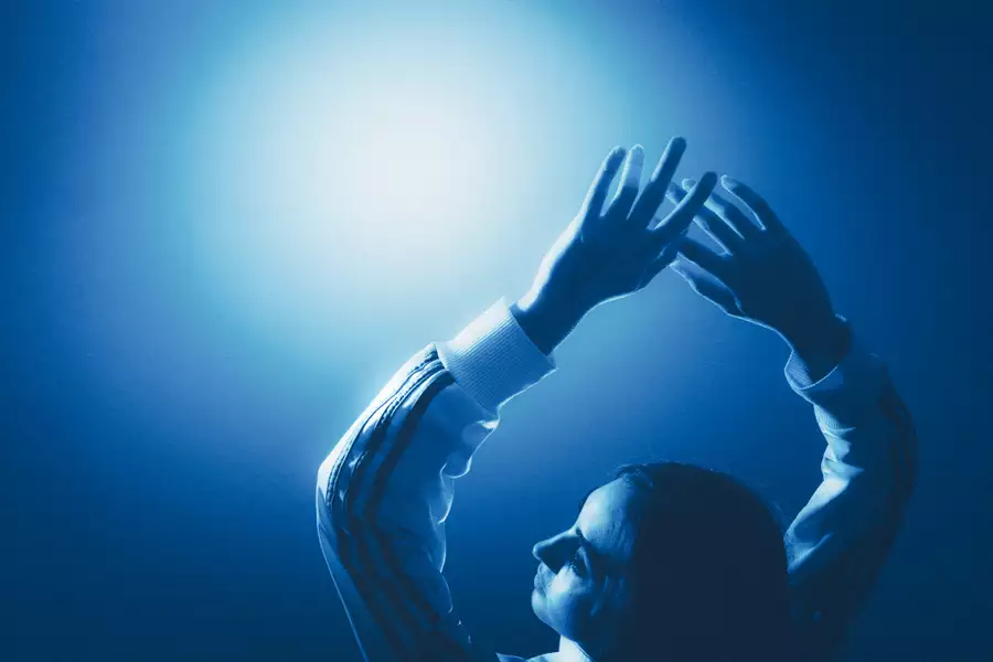 Person in blue light raising their arms overhead.