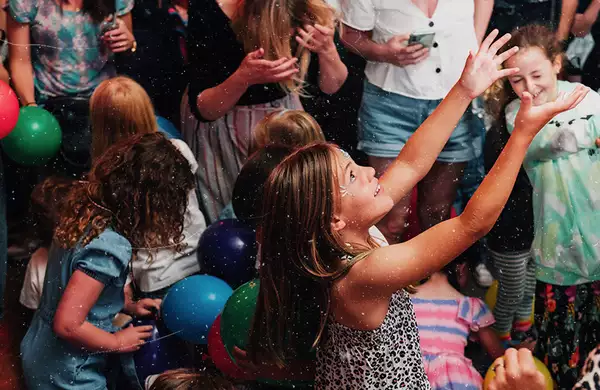 A child throwing a balloon in the air – surrounded by other children and balloons