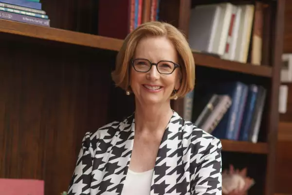 Julia Gillard smiling in front of a bookshelf