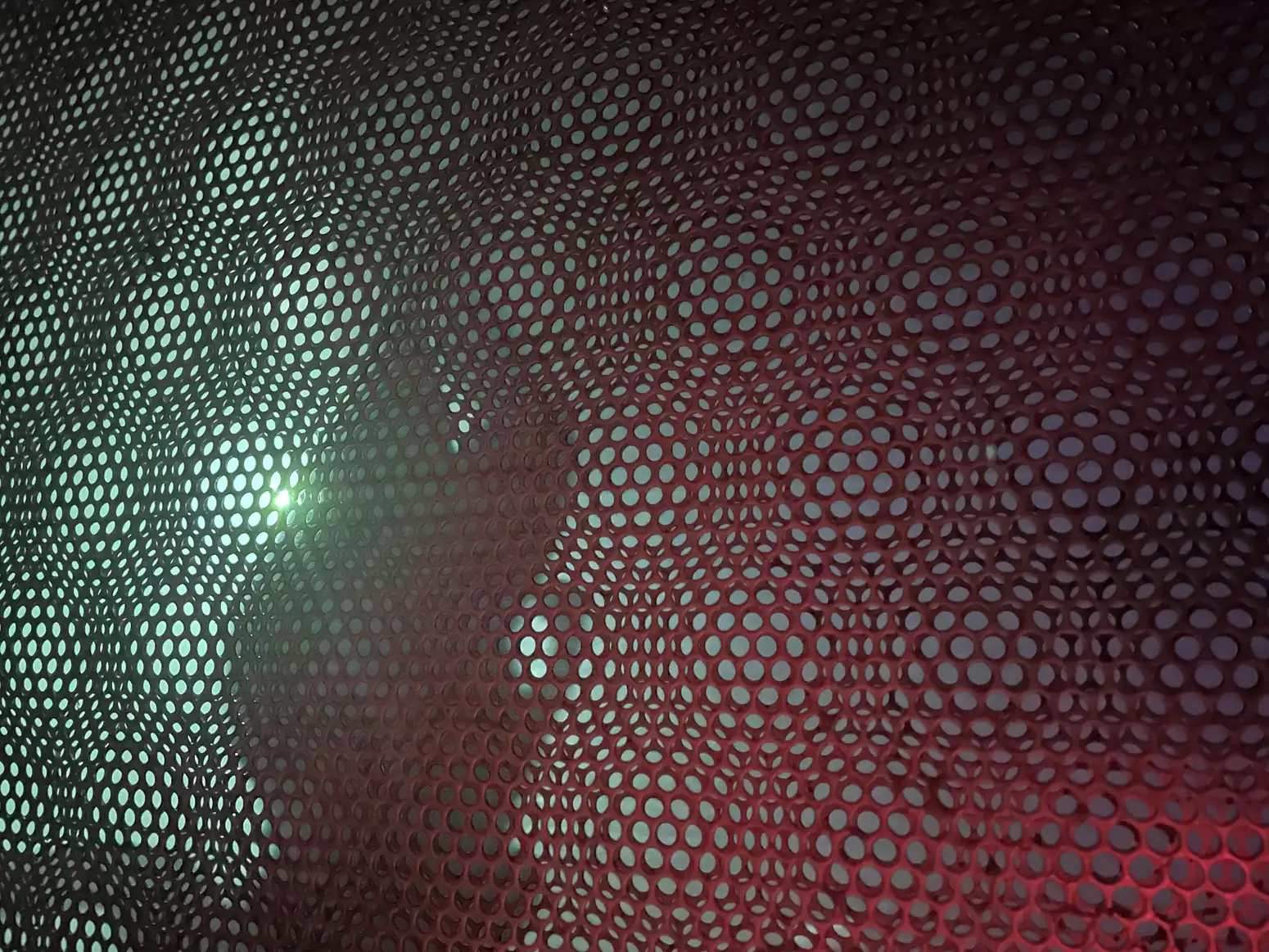 A pink plastic web with green light behind it