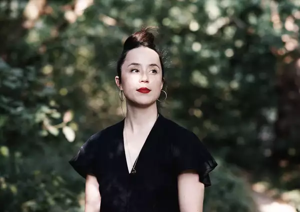 A headshot of artist and producer Luca Rutherford with greenery in the background