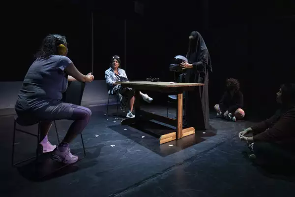 The 'BikeBurka' station, depicting a woman wearing a Burka and holding a motorcycle helmet. She is facing another woman, who has headphones on and is sat in a chair.