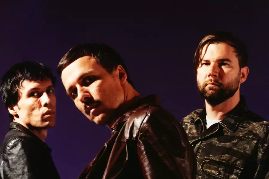 Three members of The Cribs on a dark purple background