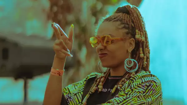 Lashimba DJing and smiling with their hand in the air.