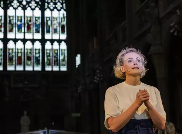 Photo of Maxine Peake performing in front of a stained glass window