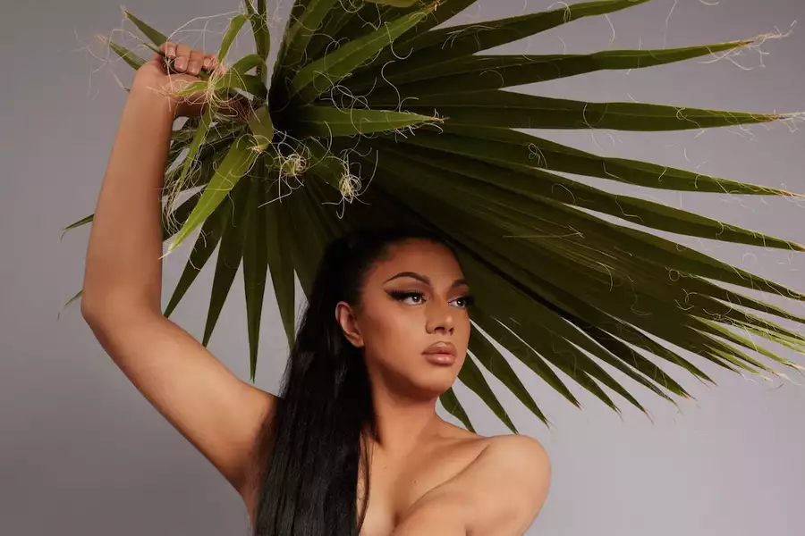 Person posing with a fan of palm leaves over their head, styled like a headdress.