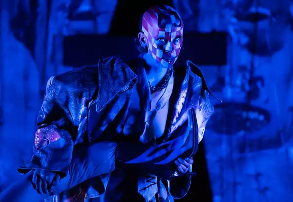 a person performing on stage in blue lighting with their face painted