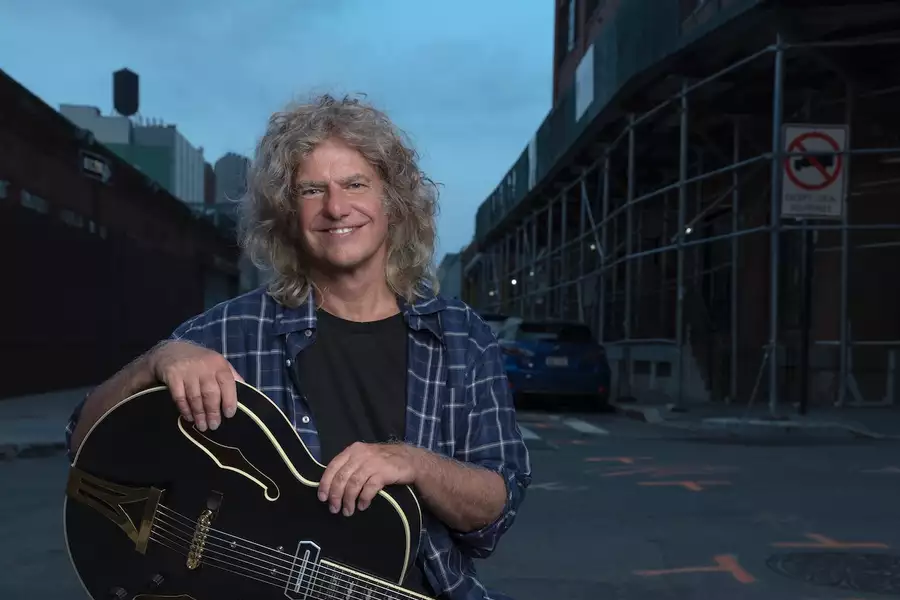 Pat Metheny with a guitar outside on a street at night