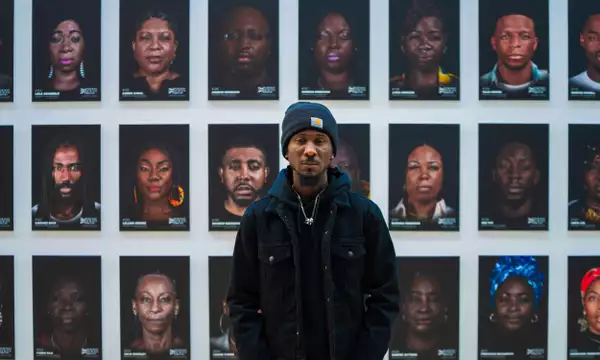Cephas Williams stood in front of a wall of his portraits