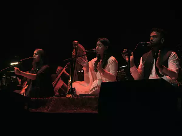A photo of three soloist singers sitting cross-legged on the floor