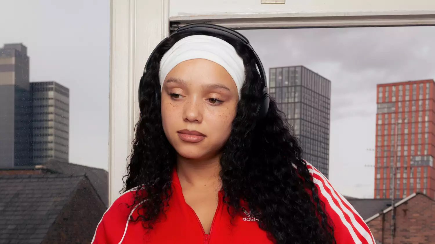 Headshot of a person waring red Adidas jacket and white headband