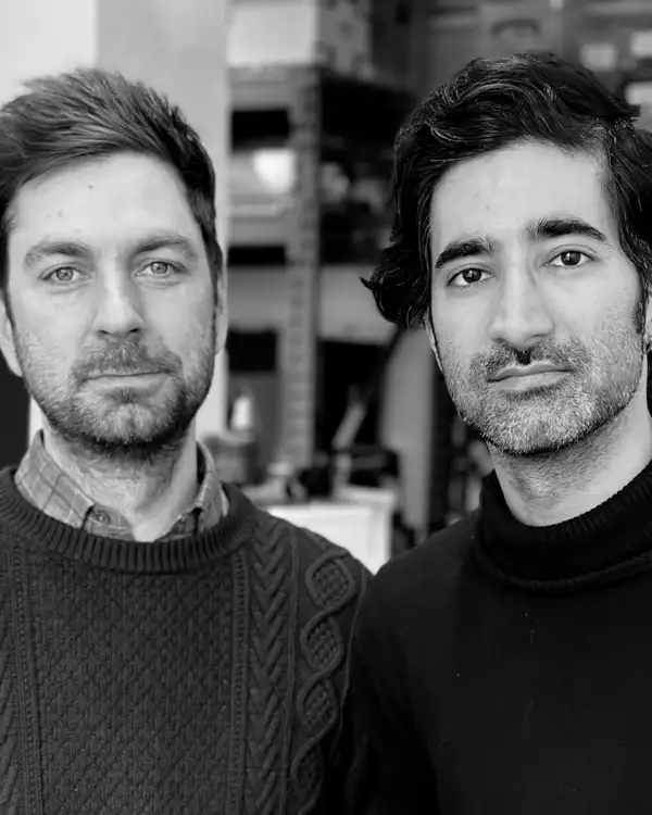 Black and white photograph of two members of AMP collective. Both are wearing jumpers.