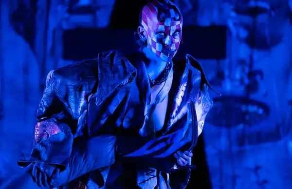a person performing on stage in blue lighting with their face painted