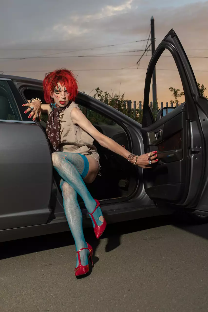David Hoyle posing in the front seat of a car, with red hair and high heels and blue stockings
