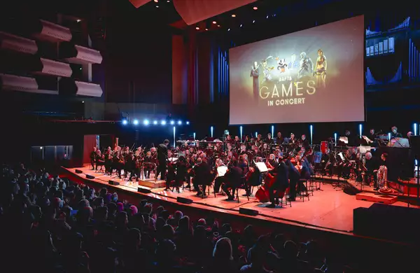 An orchestra on stage in front of a large screen which reads Bafta Games in Concert