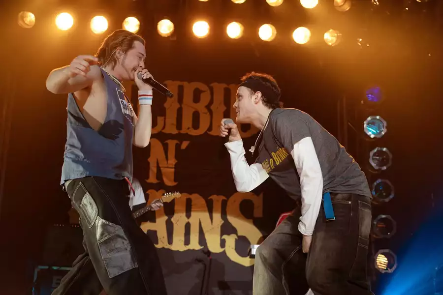A still from California Schemin' showing two men on stage singing into a microphone