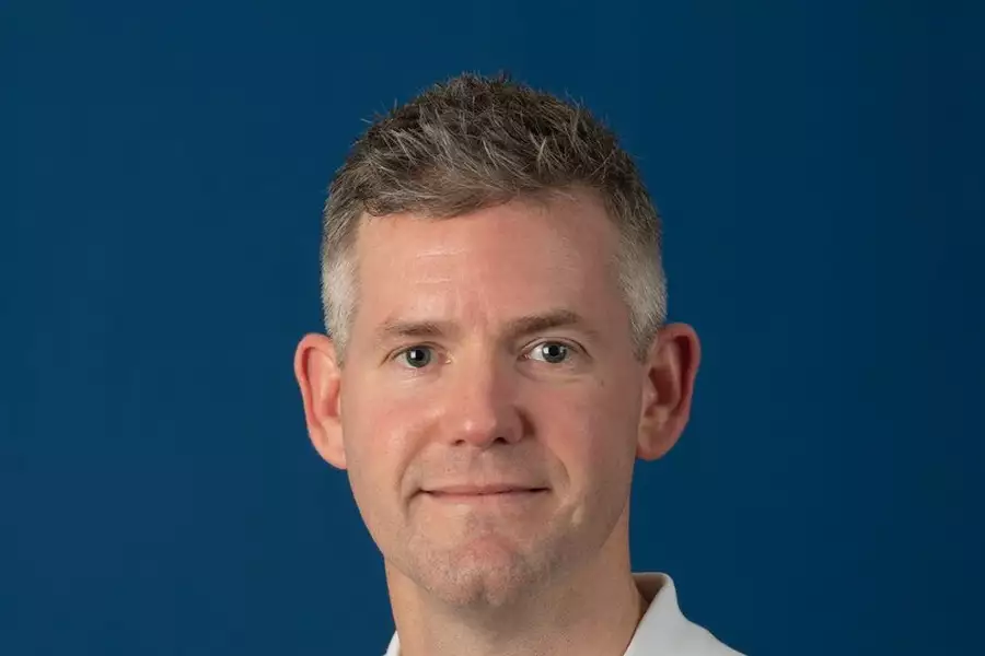 Headshot of John McFall on a blue background