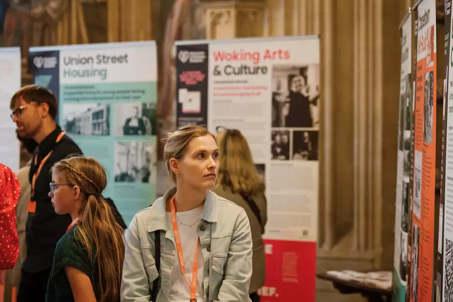 A woman looking at an exhibition of posters with a group of people in the background