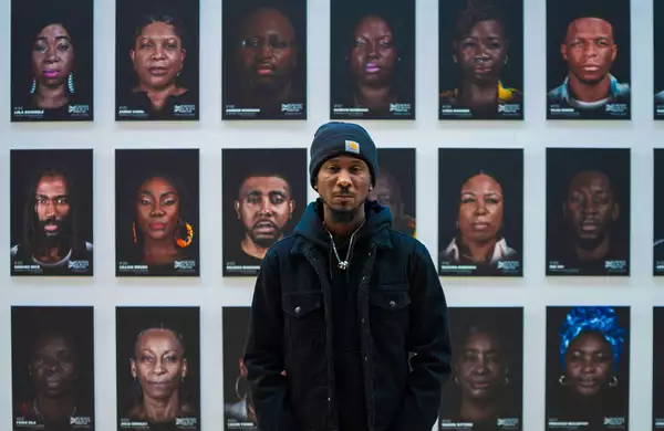 Cephas Williams stood in front of a wall of his portraits