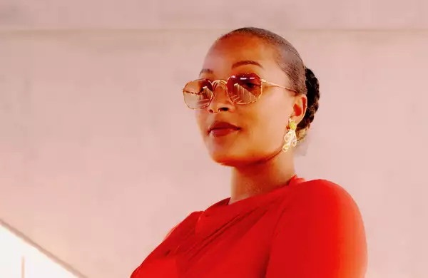 Headshot of Nubya Garcia wearing sunglasses against a pale pink-grey background