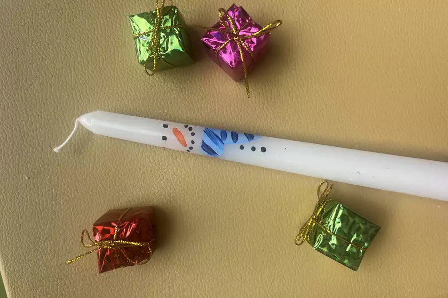 A stick candle with a snowman painted onto it