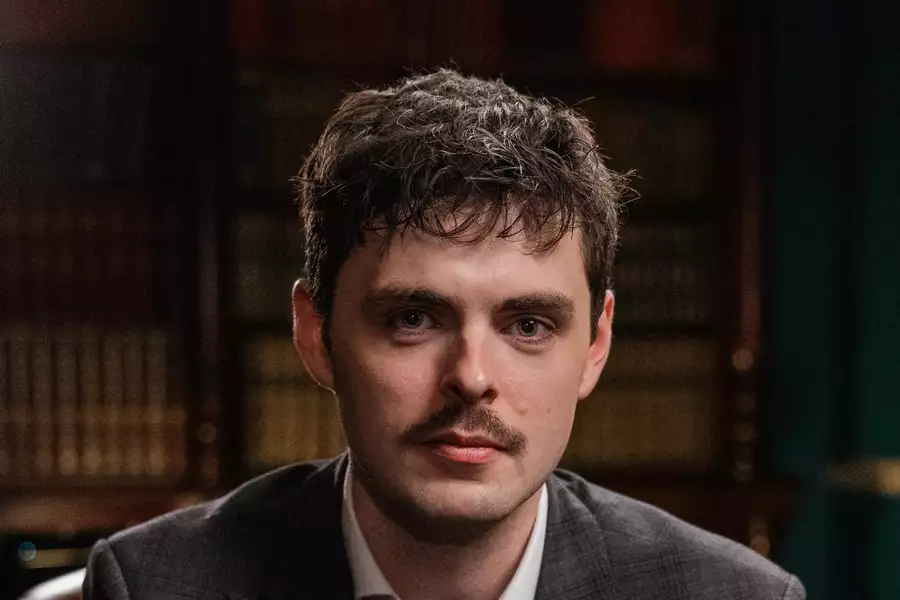 Headshot of Alex O'Connor in front of a bookshelf