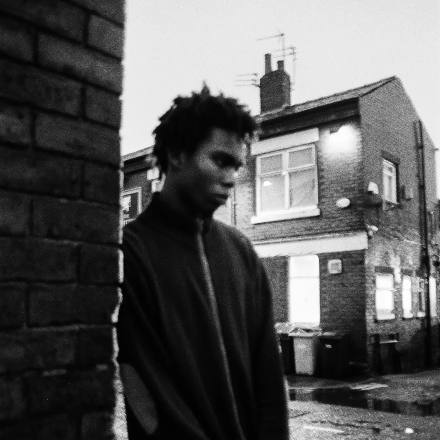 Black and white photo of Adetomiwa Ipaye stood on a street of terraced houses