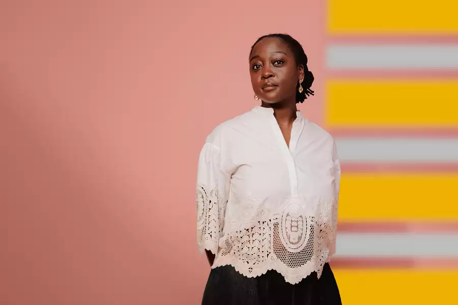 Composer Cassie Kinoshi stands in front of a pink and yellow background