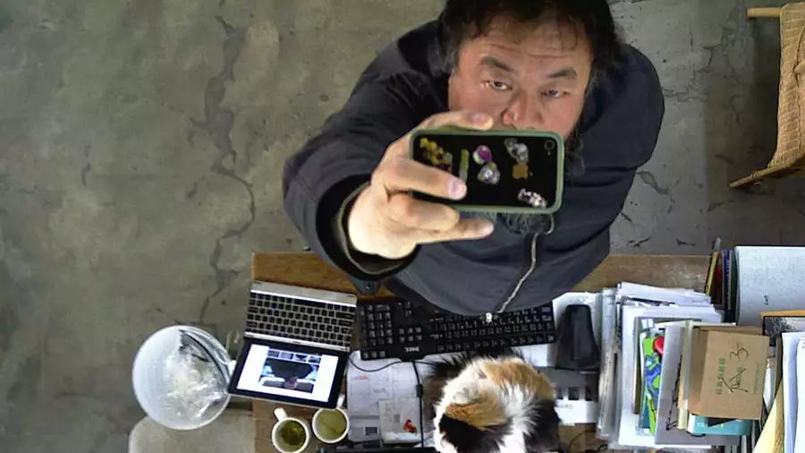 Ai Weiwei filming himself on a phone camera from above, next to a desk