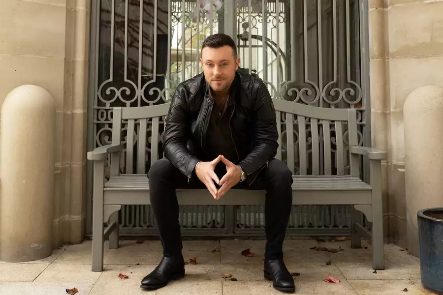 Nathan Carter sat on a bench wearing all black clothing, smiling