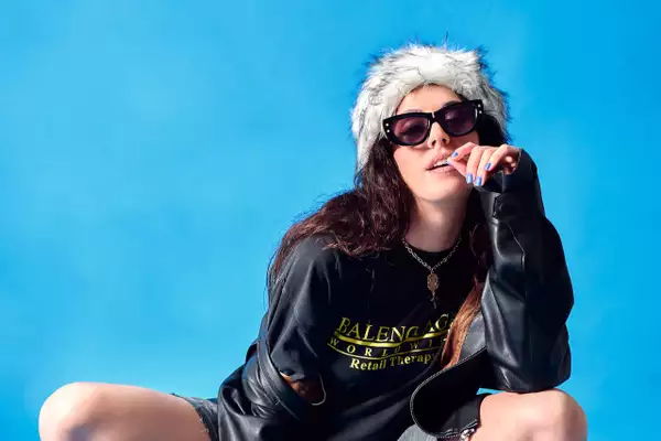 Queralt Lahoz wearing sunglasses and all-black outfit, on a bright blue background