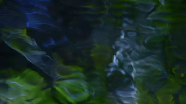 This image features a soft, abstract blend of dark blues and greens with flowing, ripple-like patterns, resembling light filtered through water or reflections on a moving surface.