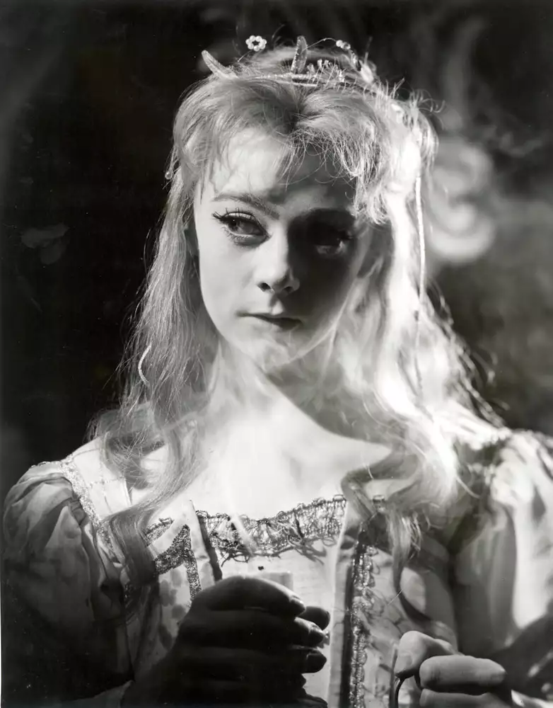 Black and white photograph of Geraldine McEwan wearing a ballgown with flowers in her hair. She is looking to the side.