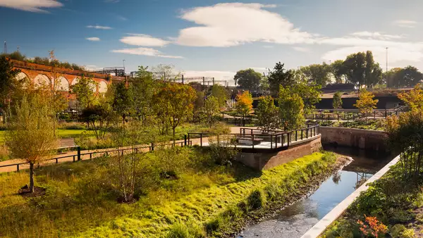 A picture of a park with lots of greenery and a small river flowing through the middle