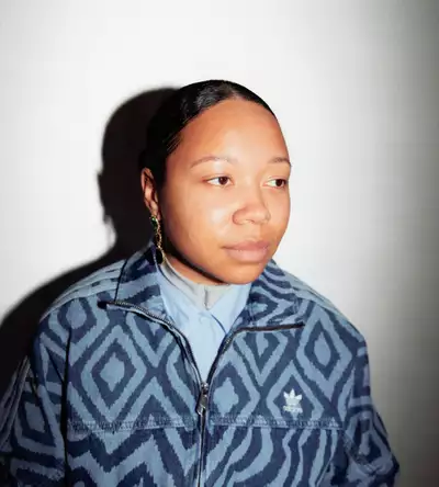 Kymara Akinpelumi wearing a patterned denim Adidas jacket on a white background
