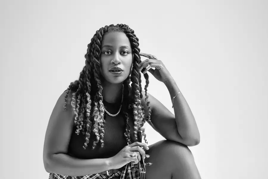 A black and white photograph of musician Rebekah Reid posing with a violin