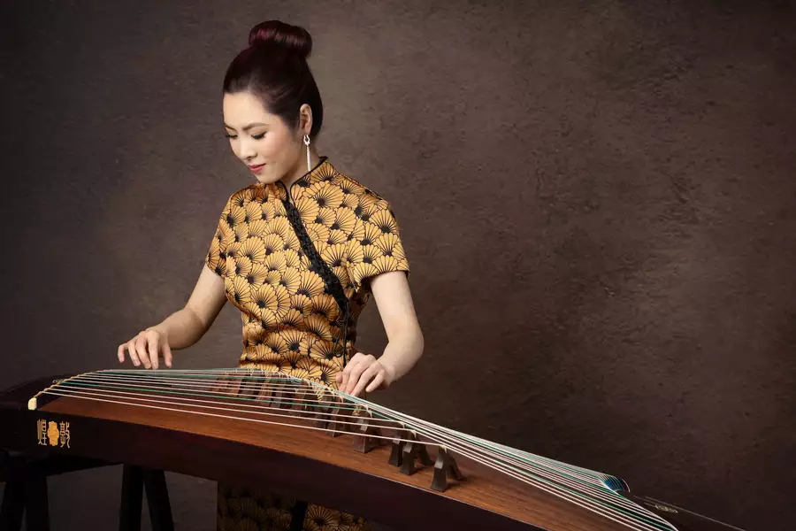 Belle playing the guzheng – against a brown background