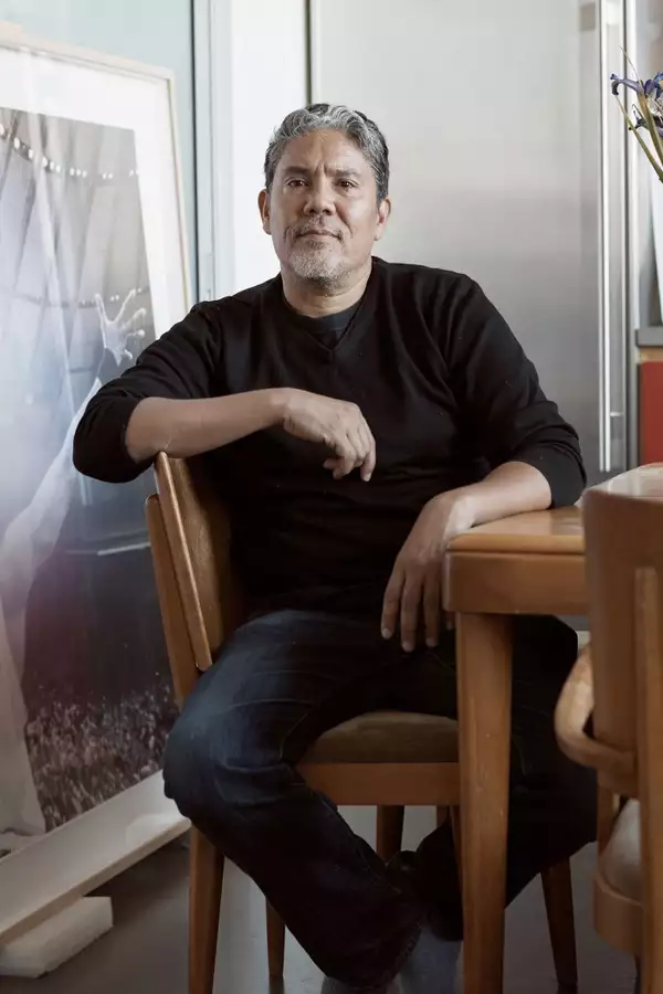 Paul Pfeiffer sat down at a wooden table next to a large artwork