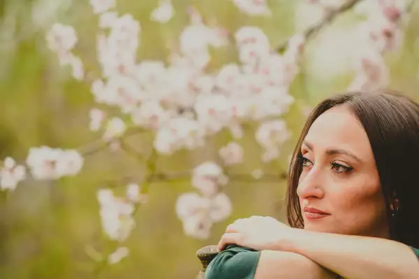 Zarina Prvasevda looking to the side. The background is blurred and shows pink blossom on a tree.