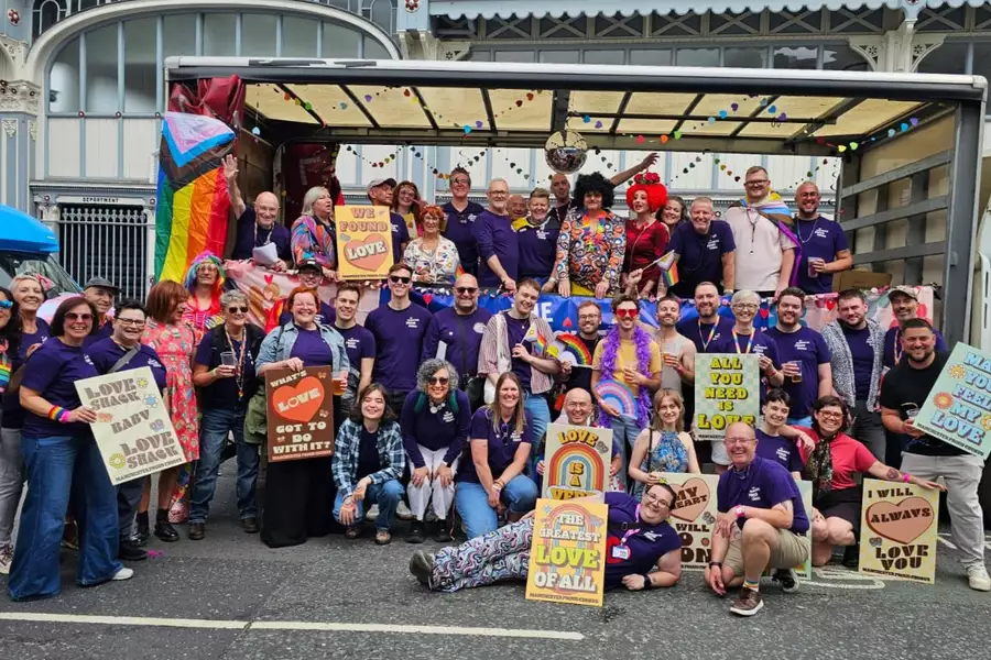 Group photo of Manchester Proud Chorus with signs about love and LGBTQ+ flags