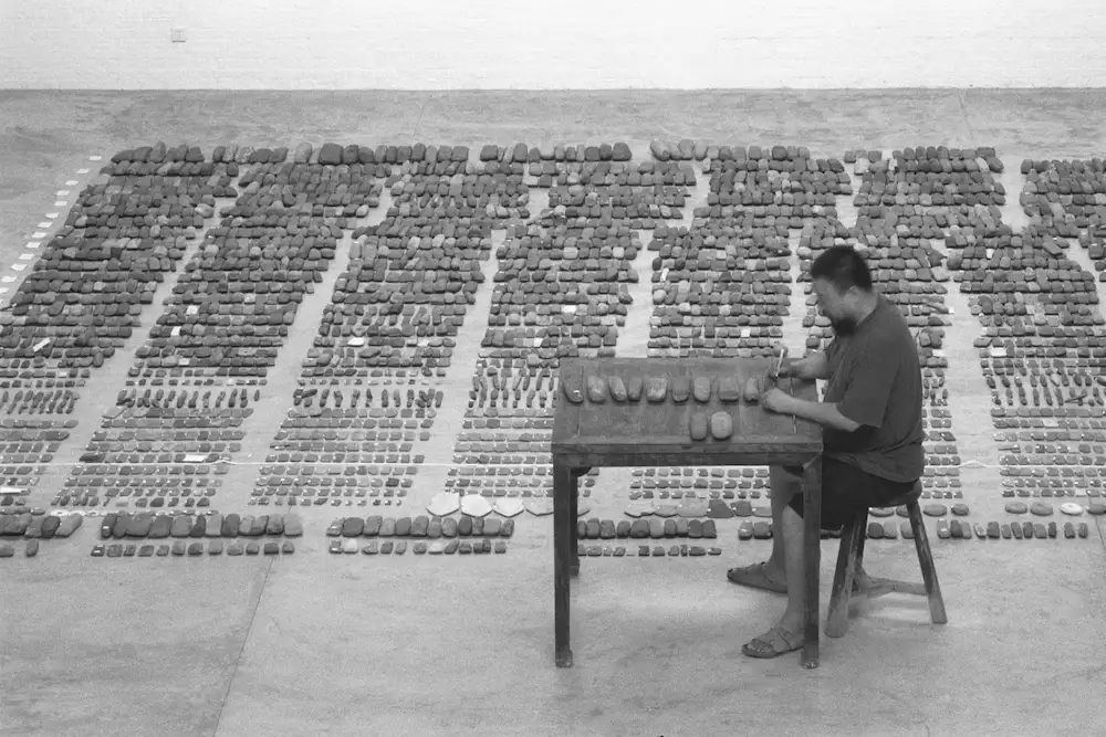 Black and white photo of Ai Weiwei working in his studio