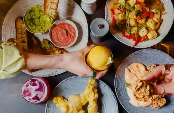 Three people pick small plates with Thai street food