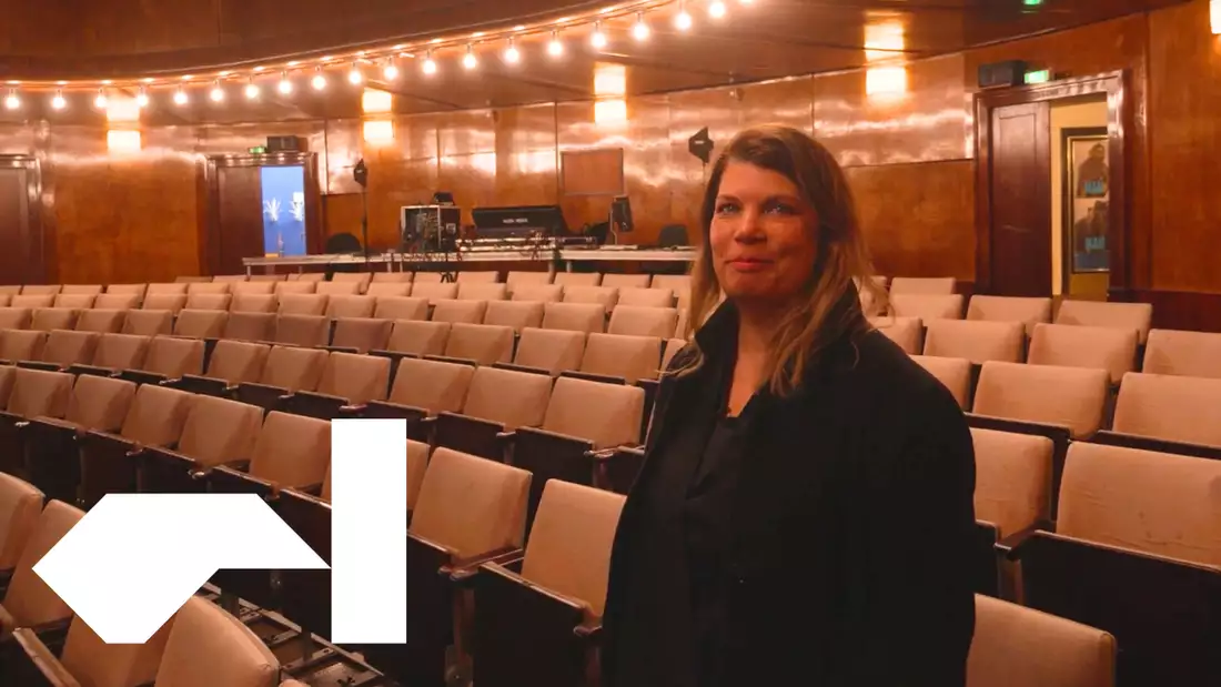 Helgard Haug of Rimini Protokoll stands in front of a map of the world