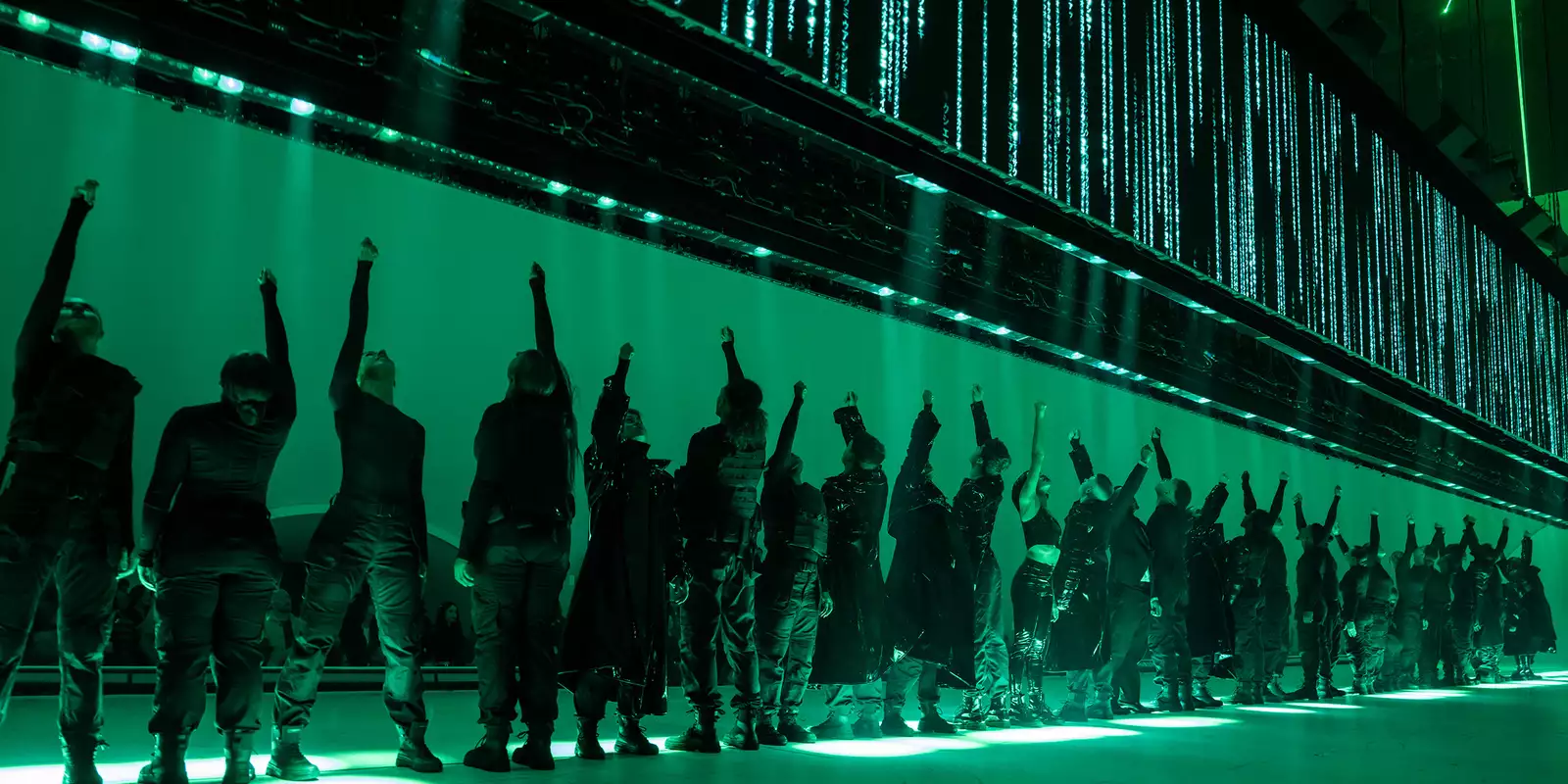 The full cast on stage for Free Your Mind lit up by green lighting