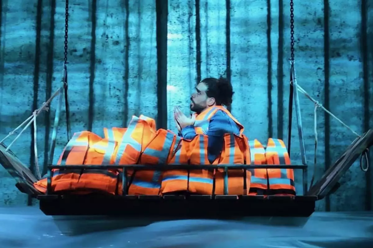 A person on stage in a boat with lifejackets