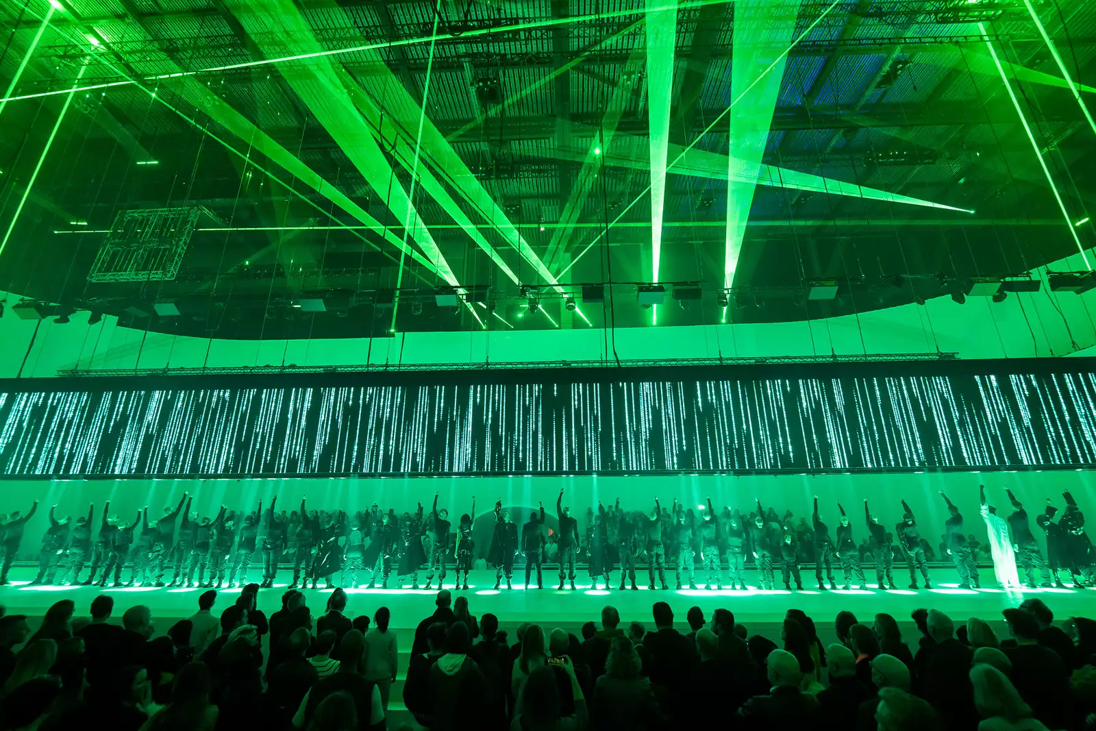 The full cast on stage in Free Your Mind lit up by lasers and green lights