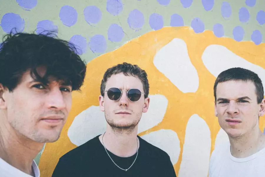 Photo of three members of Big Society in front of a colourful background