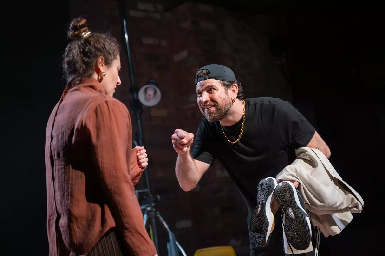 A man and a woman raise their closed fists to each other in recognition.